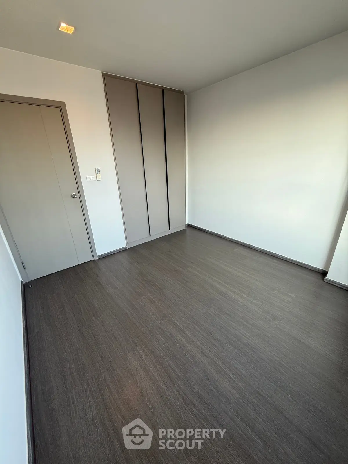 Spacious empty room with sleek wooden flooring and built-in closet, perfect for customization.