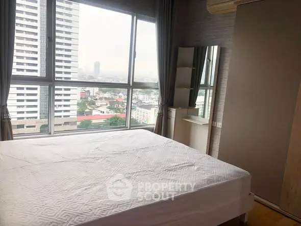 Spacious bedroom with large windows offering a stunning city view.