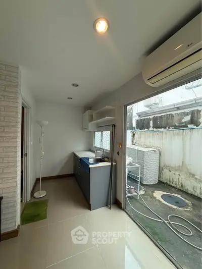 Compact kitchen with sliding glass door to outdoor area, featuring air conditioning and modern cabinetry.