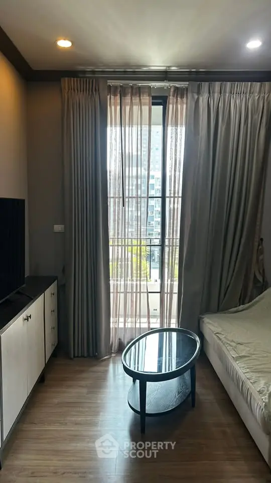 Modern living room with large window and stylish furniture in a high-rise apartment.