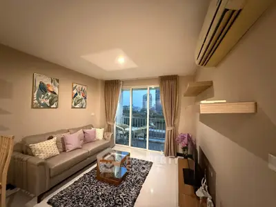 Modern living room with elegant decor and city view from balcony, featuring cozy sofa and stylish coffee table.