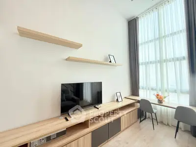 Modern living room with sleek TV unit and large window for natural light.