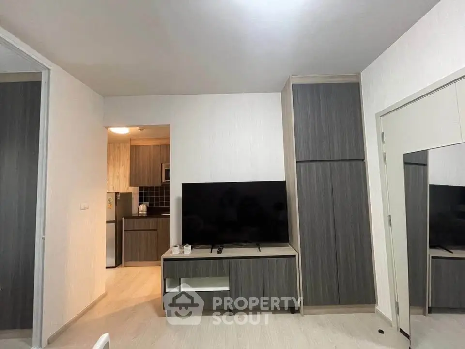 Modern living room with sleek TV unit and view into stylish kitchen