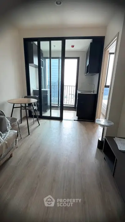 Modern apartment with open layout and balcony view, featuring sleek kitchen and stylish flooring.