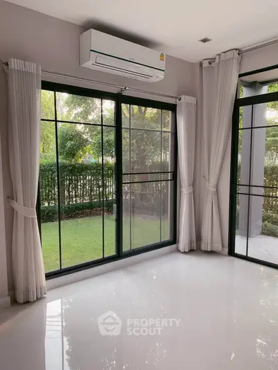 Bright living room with large windows and garden view, featuring sleek air conditioning unit.