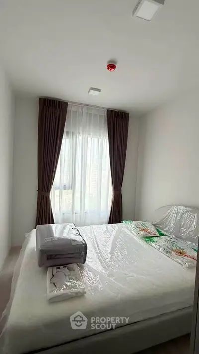 Cozy bedroom with large window and modern furnishings in a bright apartment.