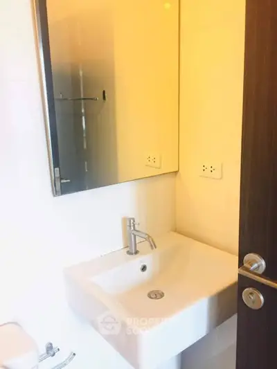 Modern bathroom with sleek sink and large mirror in a minimalist design.
