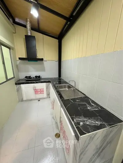 Modern kitchen with sleek black countertops and gas stove in a well-lit space.