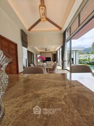 Luxurious open-plan living room with high ceilings and elegant decor, featuring a stunning view through large windows.