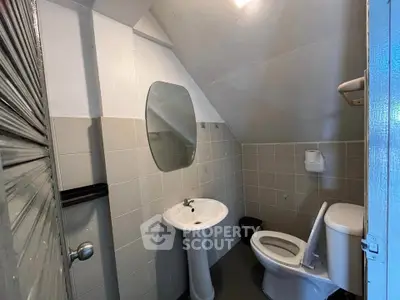 Compact bathroom with pedestal sink and toilet under sloped ceiling