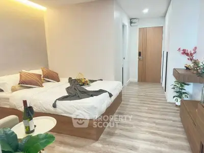 Modern bedroom with stylish decor and wooden flooring, featuring a cozy bed and elegant furnishings.