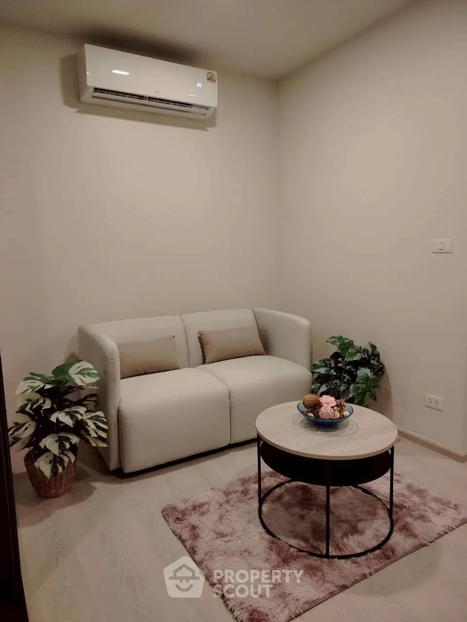 Cozy living room with modern sofa, air conditioning, and stylish decor plants.