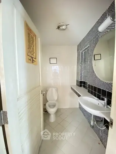 Modern bathroom with stylish black and white tiles and round mirror