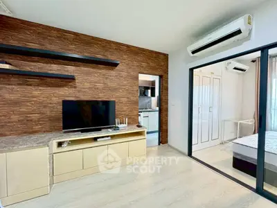 Modern living room with wood accent wall and sliding glass doors to bedroom