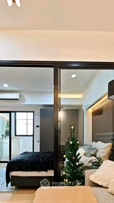 Modern living room with cozy decor and sliding glass doors leading to a stylish bedroom.