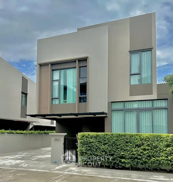 Modern two-story house with sleek design and large windows in a suburban neighborhood.