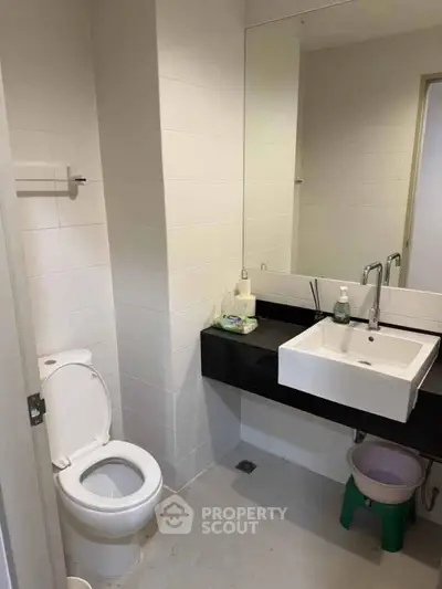 Modern bathroom with sleek white fixtures and large mirror