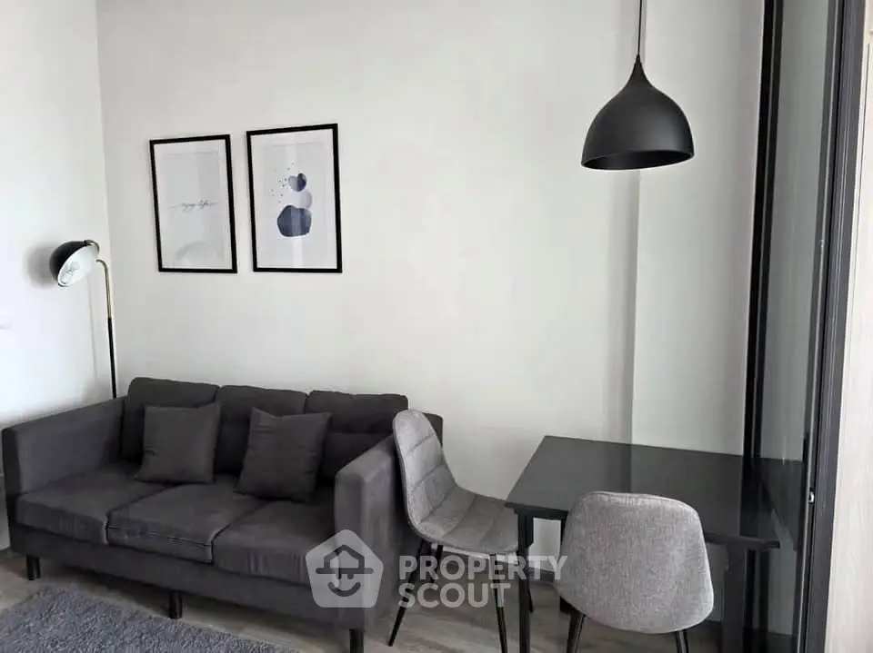 Modern living room with stylish gray sofa and dining area, featuring contemporary decor and lighting.