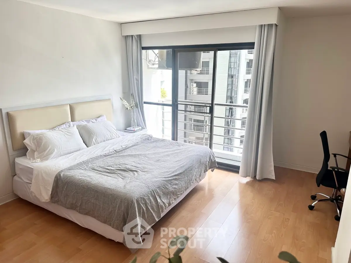 Spacious bedroom with large window and modern decor in urban apartment