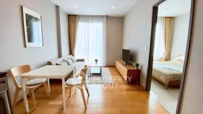 Modern open-plan living room with dining area and bedroom, featuring wooden flooring and natural light.