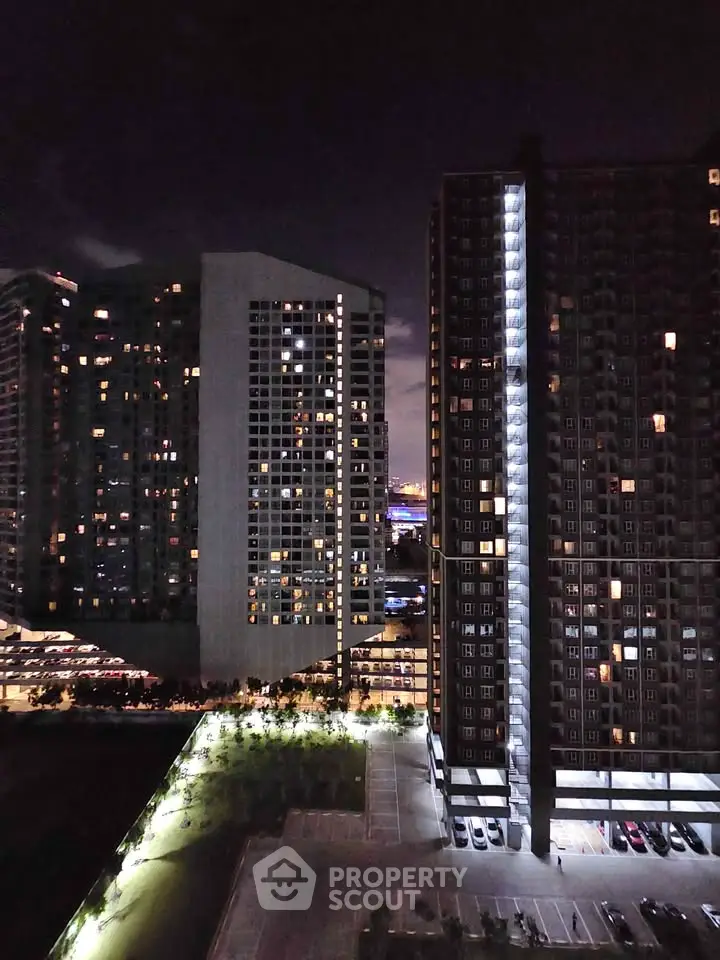 Stunning night view of modern high-rise apartment buildings with illuminated windows and cityscape backdrop.