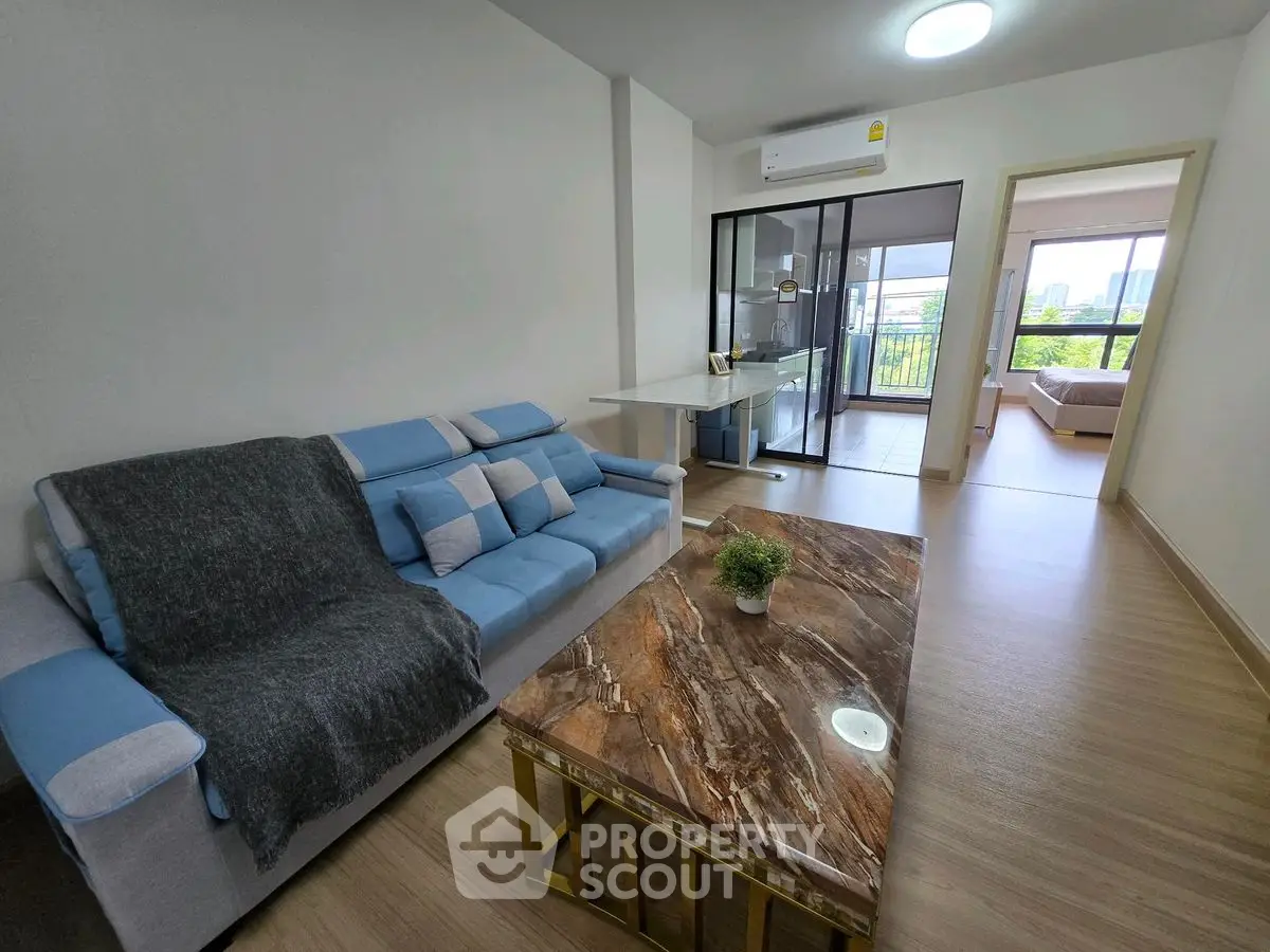 Modern living room with stylish sofa and marble coffee table, open layout to balcony and bedroom.