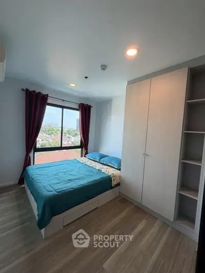 Modern bedroom with large window and built-in wardrobe offering a cozy and bright living space.