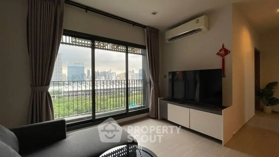 Modern living room with large window offering stunning city view and sleek furnishings.