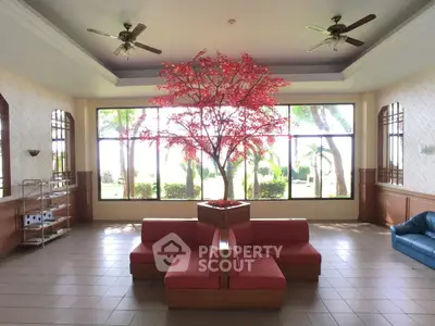Spacious living room with modern red seating and large windows showcasing garden view.