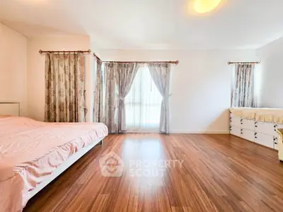 Spacious bedroom with elegant curtains and wooden flooring, perfect for a serene living experience.