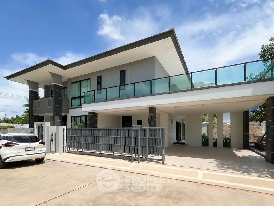 Modern two-story house with large balcony and sleek design, featuring a spacious driveway and contemporary architecture.