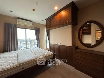 Spacious bedroom with wooden furniture and large window offering city views