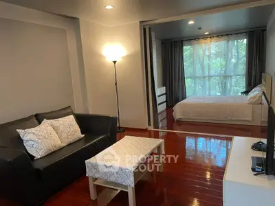 Modern studio apartment with cozy living area and large window view.