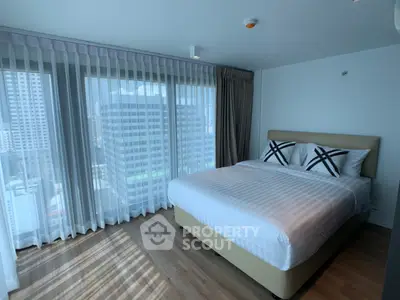 Modern bedroom with city view and large windows in a high-rise apartment.