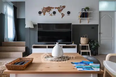 Modern living room with stylish decor and large TV, featuring a world map wall art and cozy seating area.