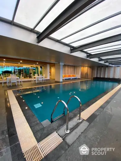 Luxurious indoor pool with modern design and seating area in upscale property