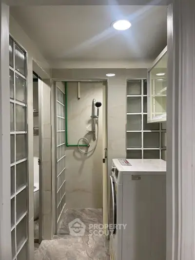 Compact bathroom with modern shower and washing machine in sleek design.
