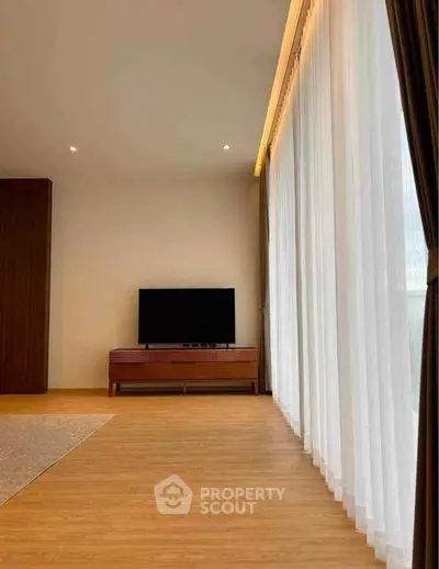 Spacious living room with large windows and modern TV setup