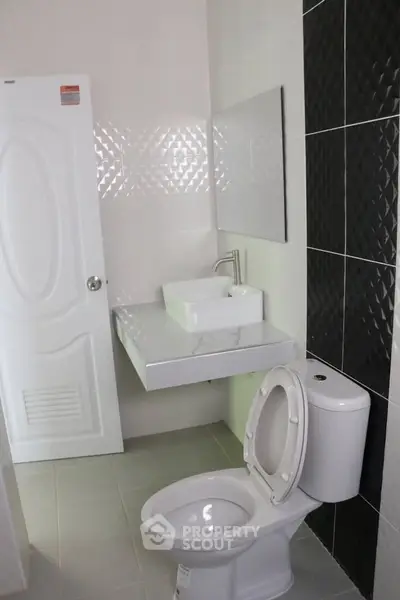 Modern bathroom with sleek fixtures and stylish black tile accent wall.