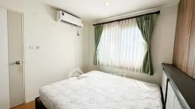Cozy bedroom with natural light, featuring a comfortable bed and air conditioning for a relaxing retreat.
