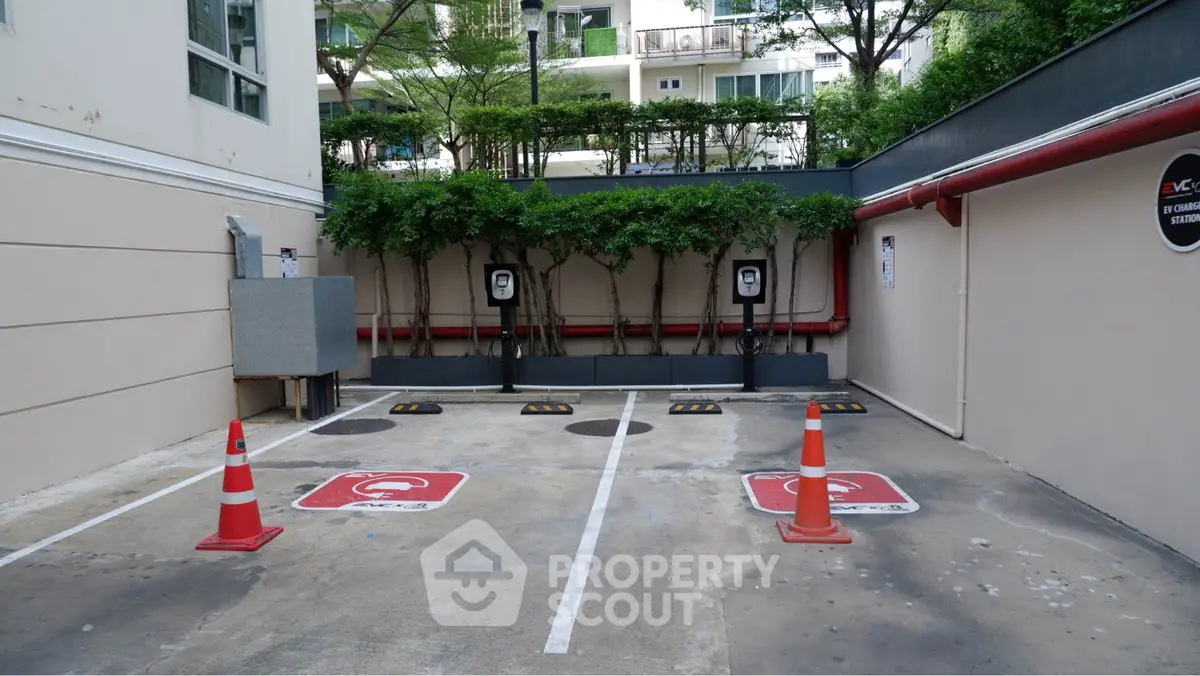 Modern parking area with electric vehicle charging stations and safety cones.