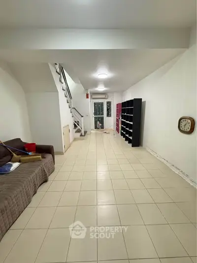 Spacious tiled living area with staircase and shelving, ideal for modern living.