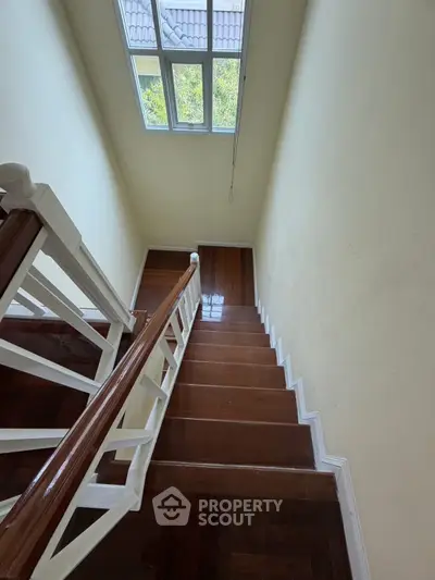 Elegant wooden staircase with natural light from window, perfect for a cozy home ambiance.