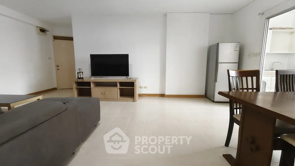 Spacious living room with modern furniture and open layout, featuring a sleek TV setup and dining area.