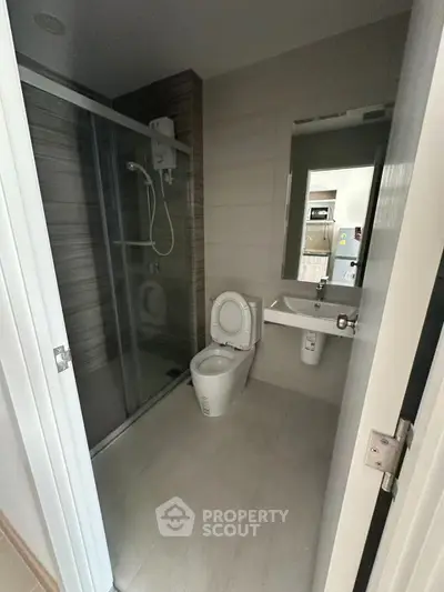 Modern bathroom with glass shower and sleek fixtures in contemporary apartment.