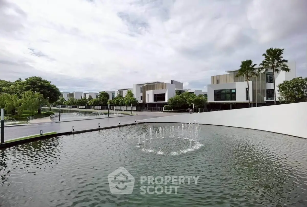 Luxurious modern villas with serene water feature and lush greenery in an upscale neighborhood.