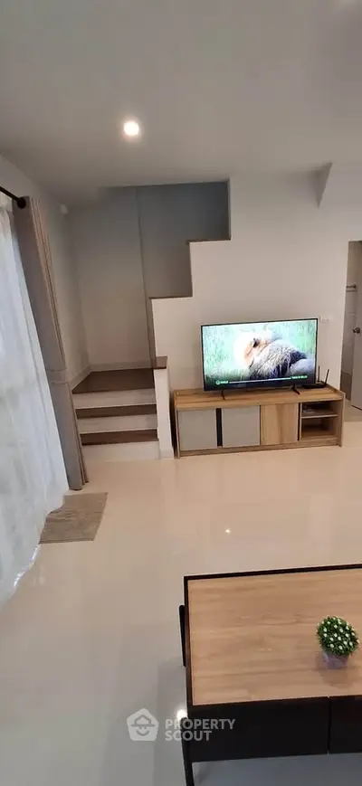 Modern living room with TV and staircase, sleek design