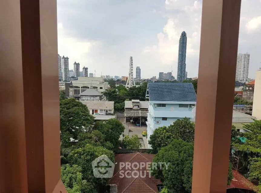 Stunning urban view from a high-rise building showcasing city skyline and lush greenery.