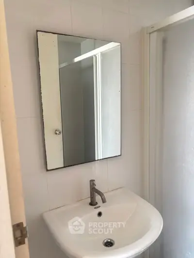 Compact bathroom with sink and mirror, ideal for small spaces.