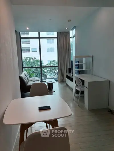 Modern living room with large windows and minimalist furniture in a bright apartment.